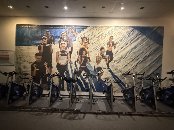 Spinningräder vor Wand mit großem Poster auf dem Menschen trainieren