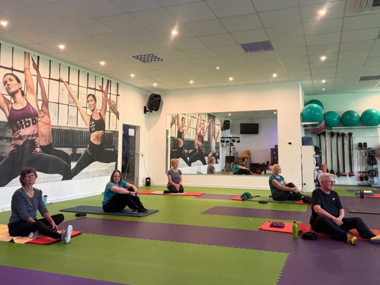 Kursteilnehmerinnen auf Matten sitzend im Kursraum