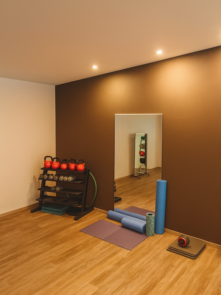 Equipment in Bauchecke, Kettleballs, Spiegel, Gewichte auf einem Ständer, Faszienrollen und Matten, Holzboden und braune und weiße Wände