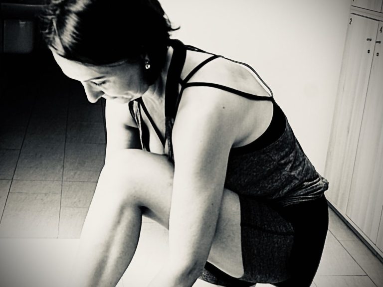 Frau in der Umkleidekabine, schwarz-weiß Aufnahme, bindet sich die Schuhe zu