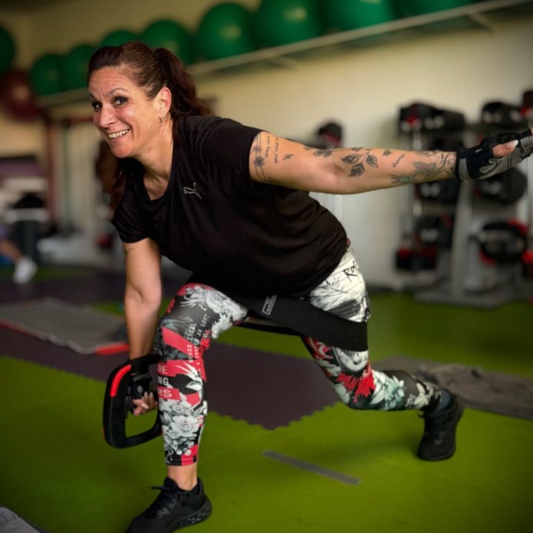 lächelnde Kursteilnehmerin mit Gewichtsscheibe in der Hand beim Training