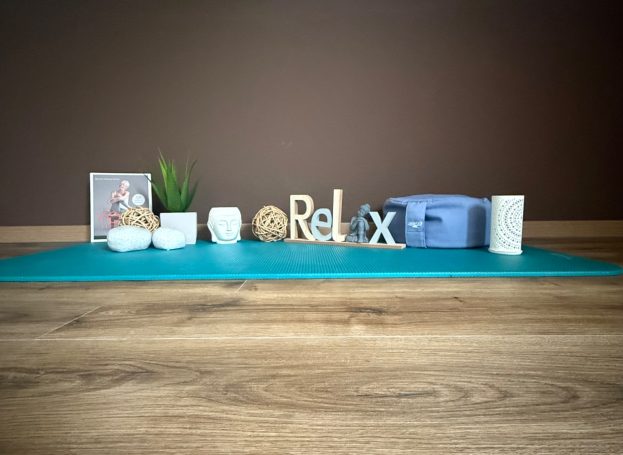 Yogamatte und Yogadeko auf Holzboden vor brauner Wand