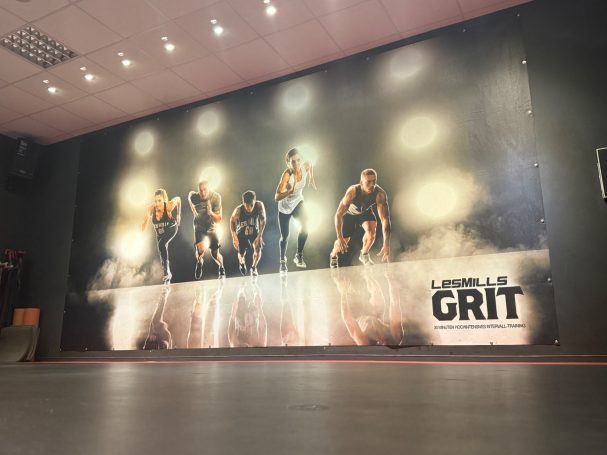 dunkler Kursraum mit wenig Beleuchtung und großem sportlichen Plakat an der Wand