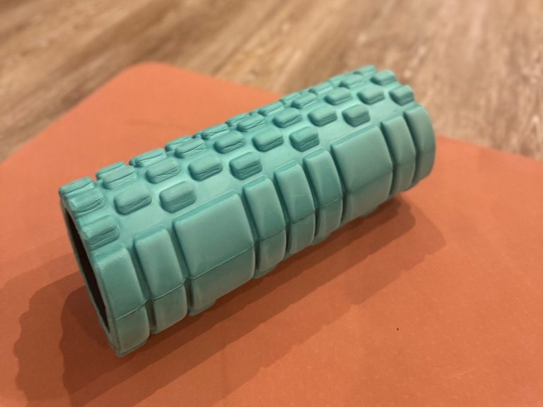 Faszienrolle in minigrün mit Struktur auf apricotfarbener Matte und darunter Holzboden