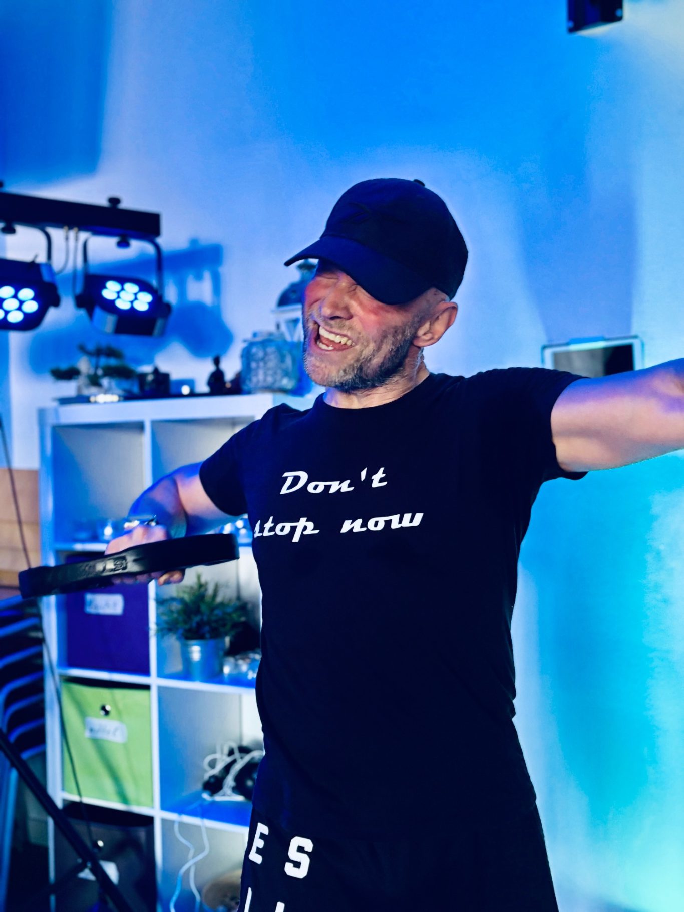 männlicher Trainer mit guter Laune, hat eine Gewichtsscheibe in der Hand